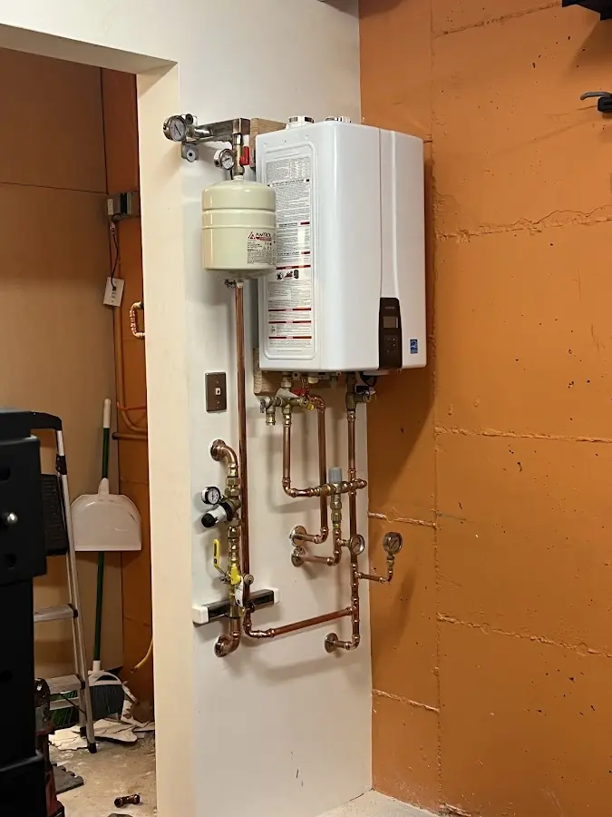 Plumbing technician inspecting water heater connections in Providence